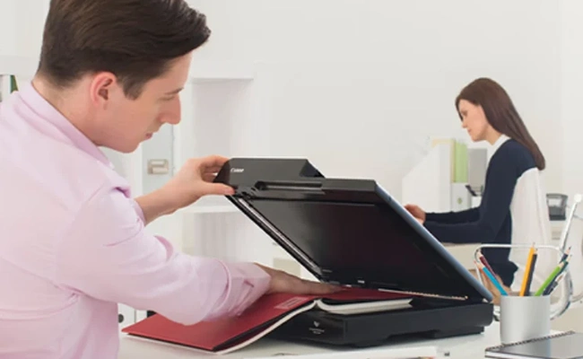 وضوح اسکنر آقایی در حال اسکن کردن کتاب با اسکنر تخت