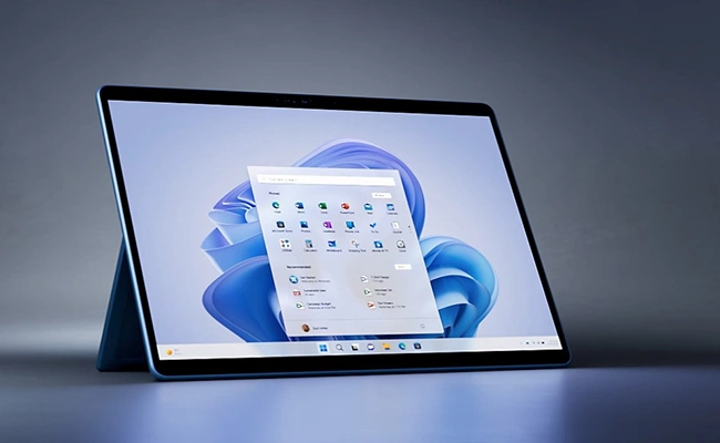 در این عکس یک تبلت مایکروسافت مدل Surface Pro 9 i7در کنار کی‌بورد و Surface Slim Pen 2 نمایش داده شده است.